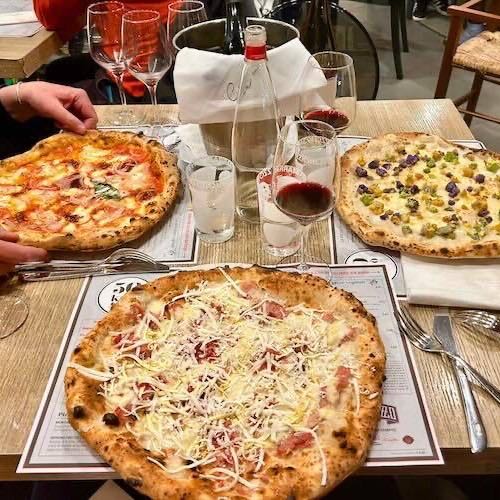 Three Neapolitan pizzas on a table at 50 Kalo in Naples