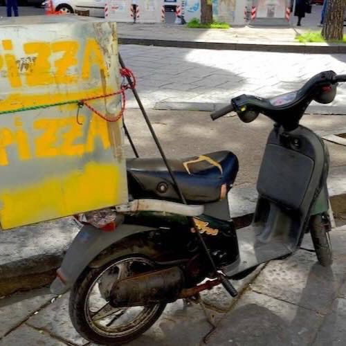 A weathered pizza delivery scooter parked on a Naples street