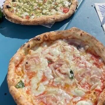 Two pizzas on a blue outdoor table at Sorbillo Lievito Madre in Naples